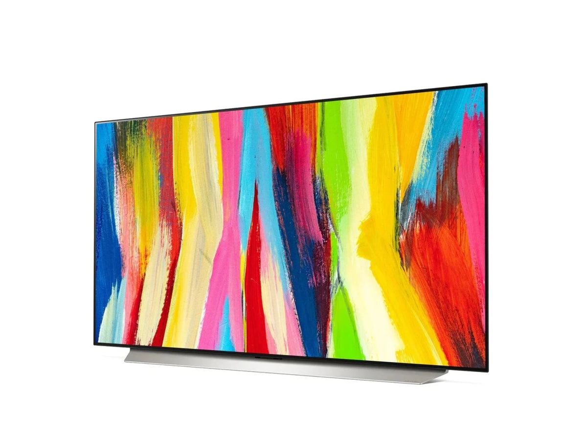 LG 83C2 OLED EVO televízió előlnézetben enyhén balra fordítva talpon, a kijelzőn színes festmény.