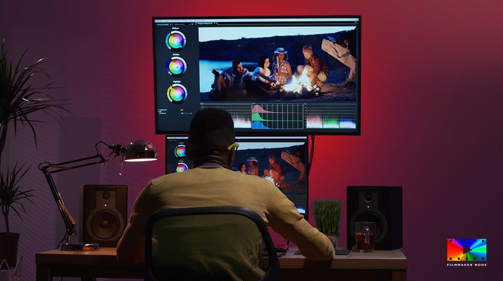 Egy férfi egy íróasztalnál ülve filmmaker mode-al dolgozik, a monitorja össze van kötve az LG 86NANO763QA TV-vel