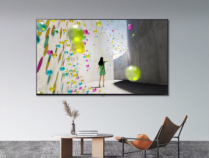 LG nanocell TV minimalista helyiségben, falra rögzítve. A TV képernyőjén egy nő és színes gömbök láthatóak.